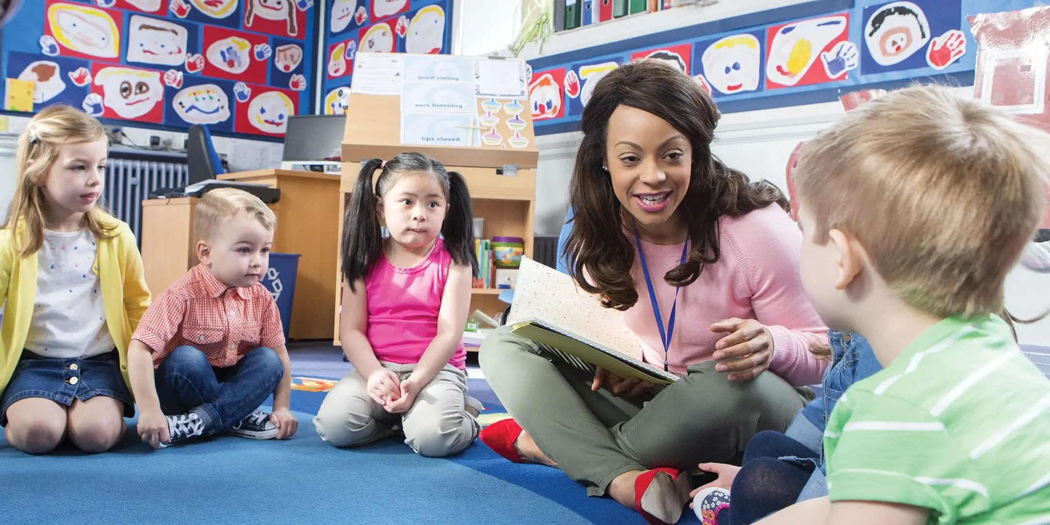Teacher reading a book to kids in a circle